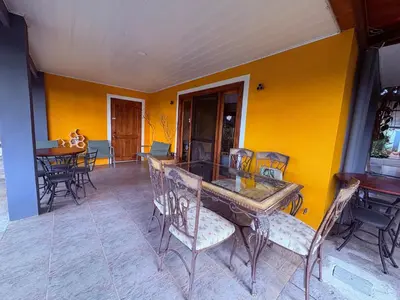 a dining room with a table and chairs and a yellow wall at Hotel Honey Bee in Alajuela City