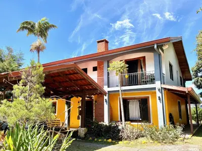 a yellow and white house with a palm tree at Hotel Honey Bee in Alajuela City