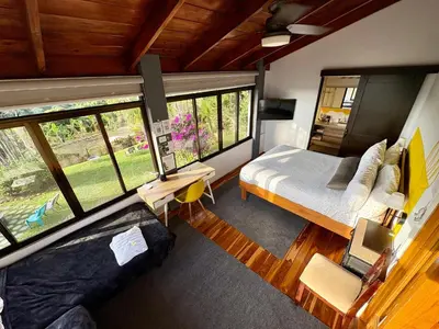 a bedroom with a bed and a large window at Hotel Honey Bee in Alajuela City