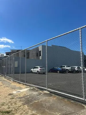 a chain link fence with cars parked in a parking lot at Hostal Canarias in San José