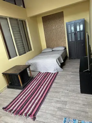 two beds in a room with a rug and a table at Hostal Canarias in San José