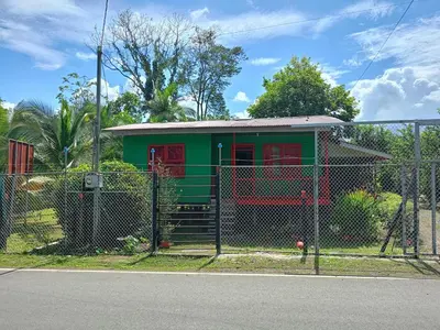 a green and red house behind a fence at The Johnson's Village in Madre de Dios