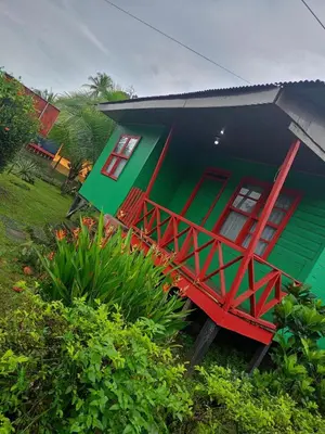 a green and red house with a red staircase outside at The Johnson's Village in Madre de Dios