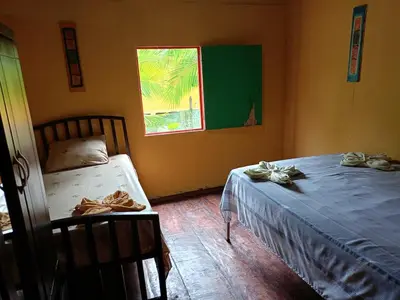 a bedroom with a bed and a chair and a window at The Johnson's Village in Madre de Dios