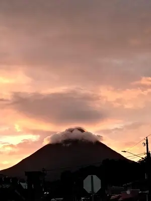 a mountain with a cloud over it with a sunset at Arenal Rainforest # La cabaña in Palma