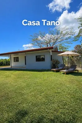 a white house with an umbrella and a lawn at Casa Tano in Delicias