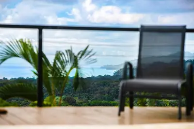 a chair sitting on top of a balcony with a view at Sunset Villa Uvita - an oceanview 4 bedroom home - no 4x4 needed in Uvita
