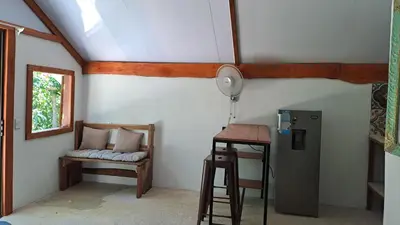 a room with a refrigerator and a chair and a table at Casa AllíS in Cóbano