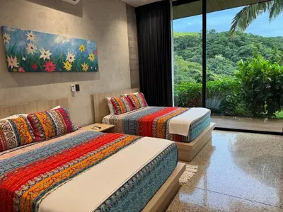 a bedroom with two beds and a window at Steady As We Go in Nosara