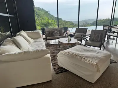 a living room with a white couch and chairs at Steady As We Go in Nosara