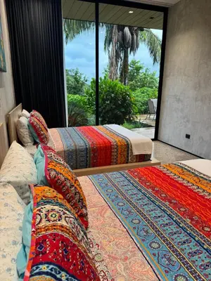 two beds in a room with a large window at Steady As We Go in Nosara