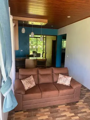 a living room with a brown couch and a kitchen at Quiet Miravalles Volcano Farm House with Pool in Bagaces