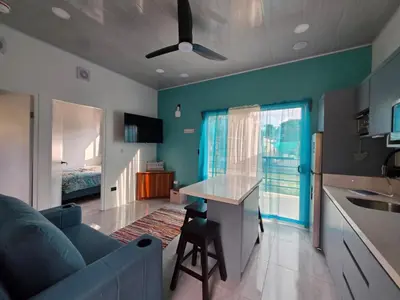 a living room with a blue couch and a kitchen at The Palm at Life's a Beach in Uvita