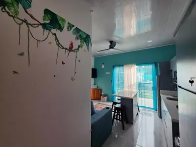 a living room with a blue couch and a kitchen at The Palm at Life's a Beach in Uvita