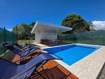 a swimming pool with chairs next to a house at The Palm at Life's a Beach in Uvita