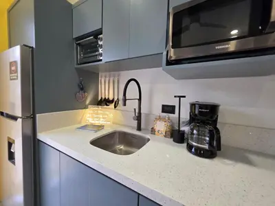 a kitchen counter with a sink and a microwave at Sunshine at Life's a Beach in Uvita