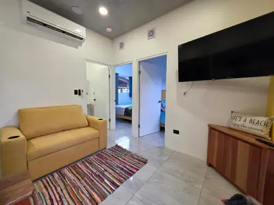 a living room with a couch and a flat screen tv at Sunshine at Life's a Beach in Uvita