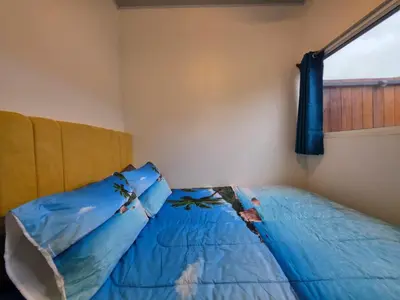 a bedroom with a blue bed with a window at Sunshine at Life's a Beach in Uvita