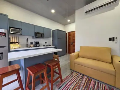a living room with a couch and a kitchen at Sunshine at Life's a Beach in Uvita