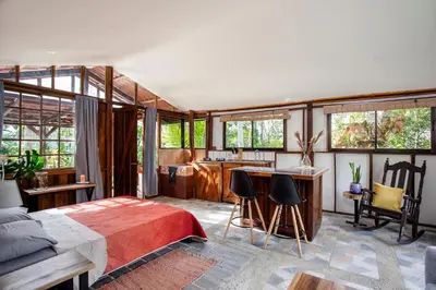 a bedroom with a bed and a kitchen at Casa Cúrcuma in Turrialba