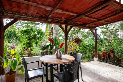 a table and chairs on a patio with a pergola at Casa Cúrcuma in Turrialba