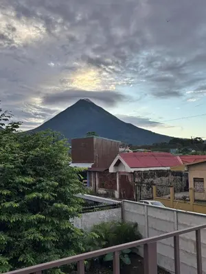 a mountain in the distance with houses and a fence at Casa Luz Volcano View La Fortuna in Fortuna