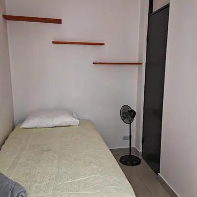 a small bedroom with a bed and a fan at Apartamentos Las Orquideas in San Pedro