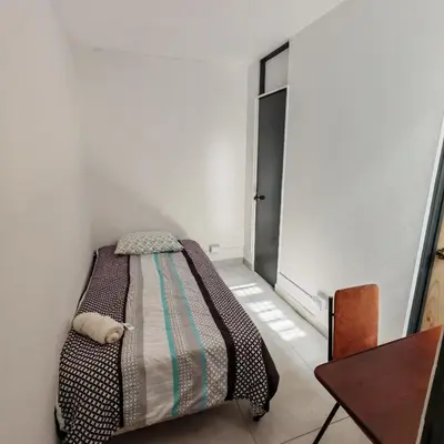 a small bedroom with a bed and a table at Apartamentos Las Orquideas in San Pedro