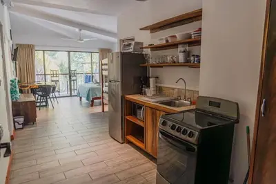 a kitchen with a stove and refrigerator and a dining room at Beachfront Studio, Private Balcony with Ocean View in Tamarindo