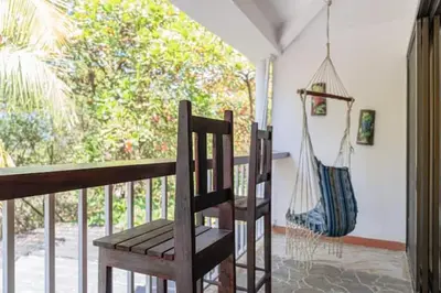 a wooden chair sitting on a porch with a hammock at Beachfront Studio, Private Balcony with Ocean View in Tamarindo