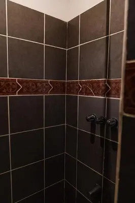 a black tiled shower with black handles in a bathroom at Beachfront Studio, Private Balcony with Ocean View in Tamarindo