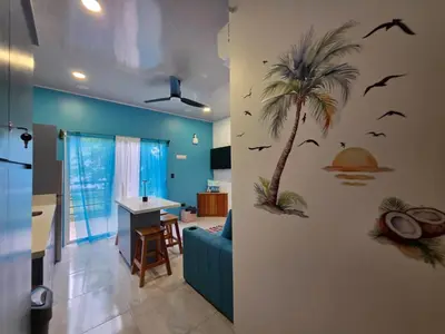 a living room with a palm tree and birds on the wall at Ocean Breeze at Life's a Beach in Uvita