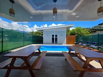 an outdoor patio with wooden picnic tables and a swimming pool at Ocean Breeze at Life's a Beach in Uvita
