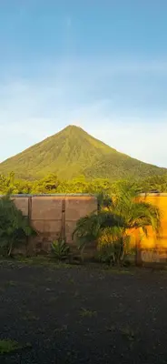 a mountain behind a wall with trees in front of it at Villas Volcan Arenal in Fortuna