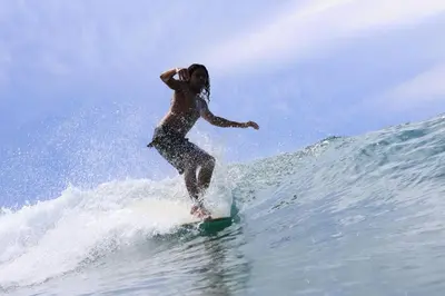 a person riding a wave on a surfboard in the ocean at 3BR Villa with Pool - 10 Min Walk to Beach & Surf in Playa Avellana