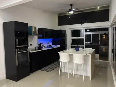 a kitchen with black cabinets and white bar stools at Family home in Cieneguita
