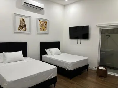 a room with two beds and a flat screen tv at Family home in Puerto Limón