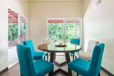 a dining room with a table and blue chairs at Mistico Beach Residence in Muñeco