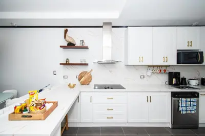 a white kitchen with white cabinets and a black appliance at Ocean-Mountain views 2 Bdr, Villa Pelicano in Dominicalito