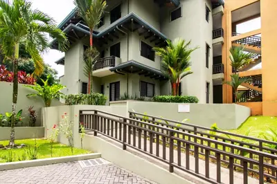 a building with a fence and palm trees at Ocean-Mountain views 2 Bdr, Villa Pelicano in Dominicalito
