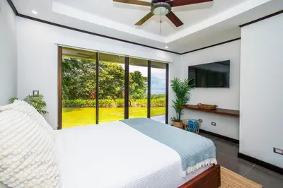 a bedroom with a white bed and a large window at Ocean-Mountain views 2 Bdr, Villa Pelicano in Dominicalito