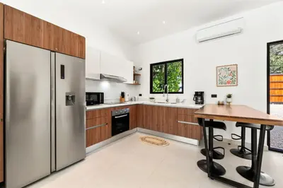 a kitchen with a stainless steel refrigerator and a wooden table at Casa 6 Palmas Jungle Hideaway with Private Pool in Tamarindo
