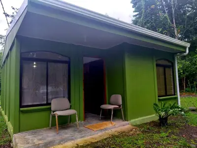 two chairs sitting in the front of a green house at Inmoexito Eco Tours in Upala