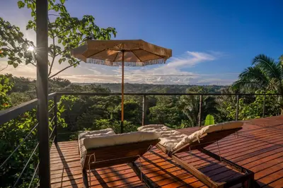 a deck with a table and chairs and an umbrella at Casa Canopy in Manzanillo