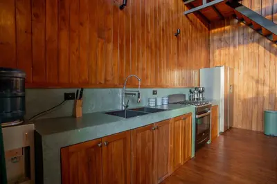 a kitchen with wooden cabinets and a sink and a refrigerator at Casa Canopy in Manzanillo