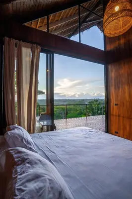 a bedroom with a bed and a large window at Casa Canopy in Manzanillo