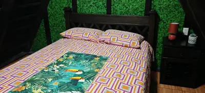 a bed with a colorful comforter and two pillows at Casa Tucán in Ángeles