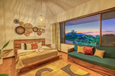 a bedroom with a bed and a couch and a window at Walk to Beach - Hot Tub - Pool - Comfort & Space in Coco