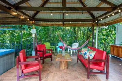 a screened in porch with red chairs and a table at Toucan River Retreat - River Access, AC & Jacuzzi in San Francisco