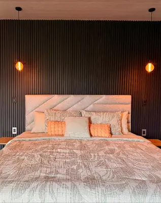 a bedroom with a large bed with orange and white pillows at Arenal Star Luxury Studios with Private Jacuzzi in Fortuna
